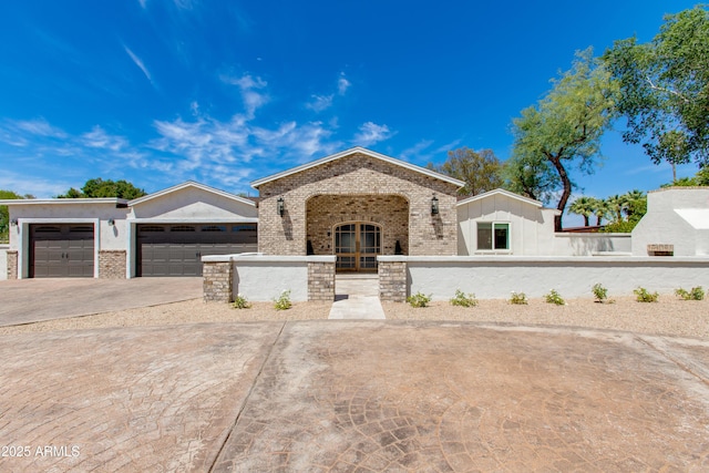 view of front of house with fence private yard, french doors, brick siding, an attached garage, and driveway