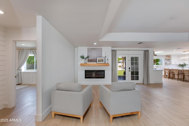 living area featuring recessed lighting, light wood-style flooring, baseboards, and a large fireplace