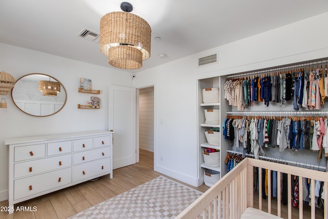 bedroom with baseboards, visible vents, wood finished floors, and a closet