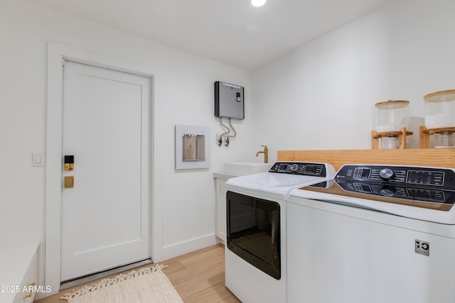 washroom with a sink, baseboards, light wood finished floors, separate washer and dryer, and recessed lighting