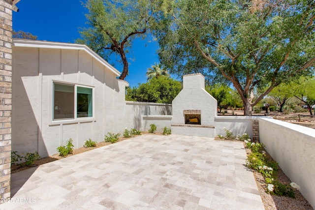 view of patio featuring an outdoor fireplace and fence