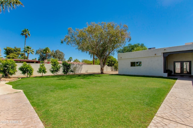 view of yard with a fenced backyard and french doors