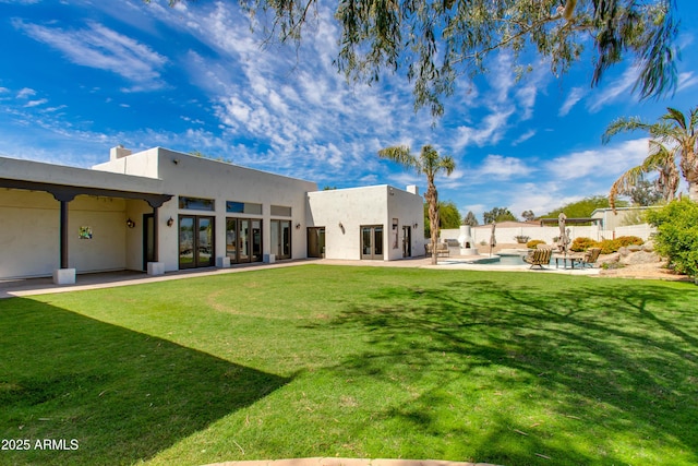 rear view of house with french doors, stucco siding, a yard, and a patio area