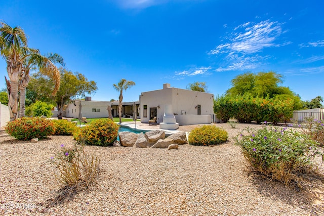 rear view of house with a patio, stucco siding, and fence