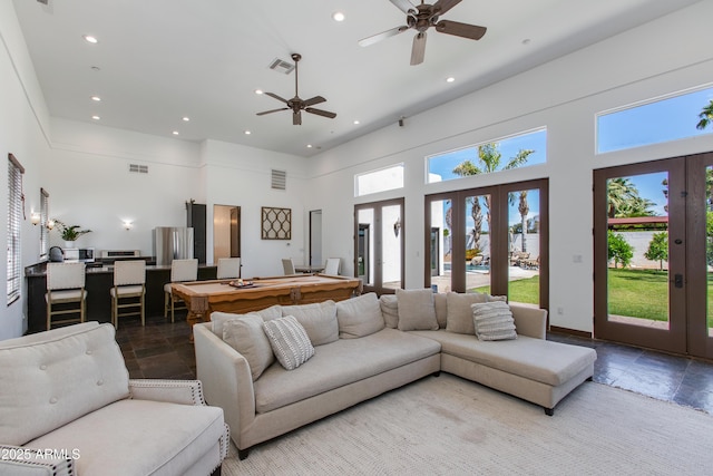 living room featuring stone tile floors, a high ceiling, visible vents, and french doors