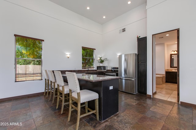 kitchen with visible vents, baseboards, appliances with stainless steel finishes, and stone tile flooring