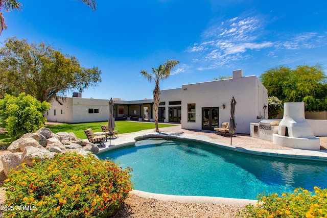 outdoor pool with a yard, a patio, and french doors