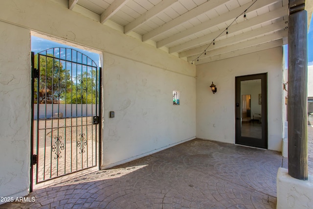 view of exterior entry with a gate and stucco siding