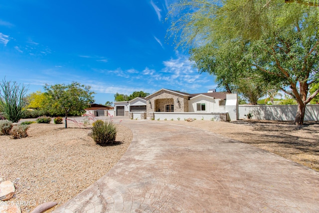 ranch-style home featuring driveway, fence private yard, stone siding, and a garage