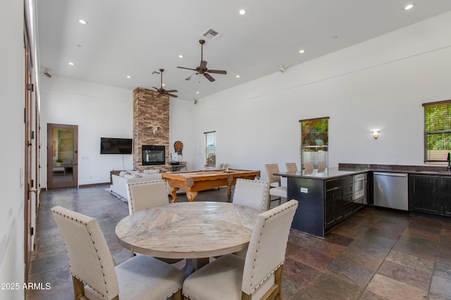 dining area with a ceiling fan, a towering ceiling, visible vents, a fireplace, and recessed lighting