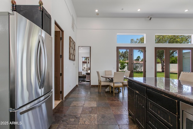 kitchen featuring freestanding refrigerator, plenty of natural light, french doors, and stone tile flooring