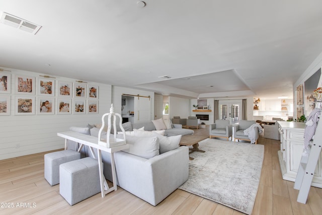 living area with visible vents, a raised ceiling, and light wood-style floors