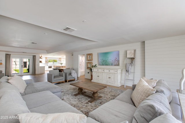 living room featuring light wood-style floors, a raised ceiling, and visible vents