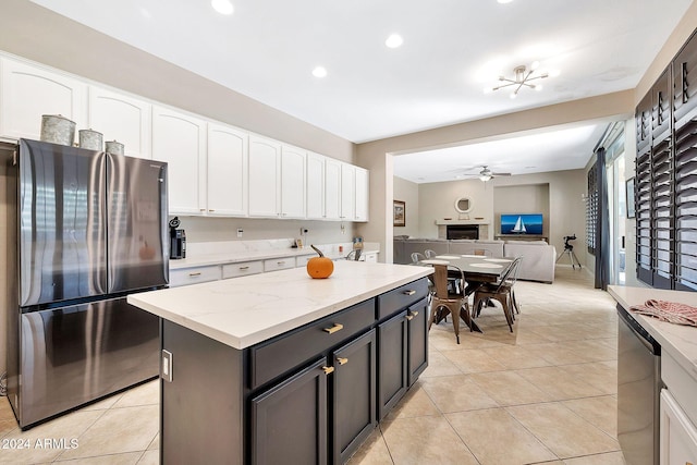 kitchen with light tile patterned flooring, white cabinets, ceiling fan, appliances with stainless steel finishes, and a kitchen island