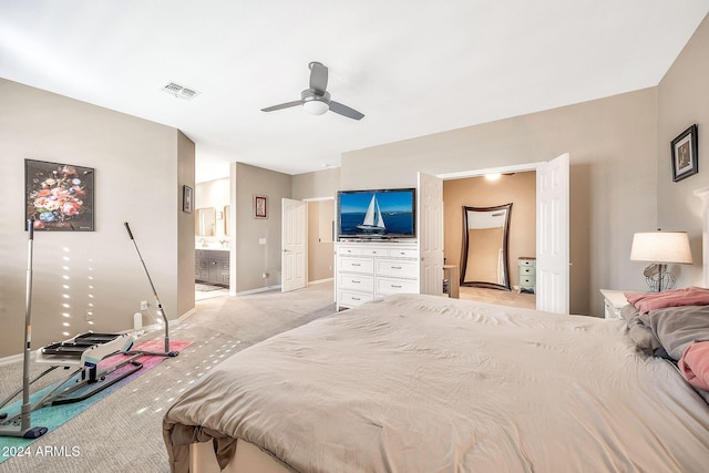 carpeted bedroom with ensuite bathroom and ceiling fan