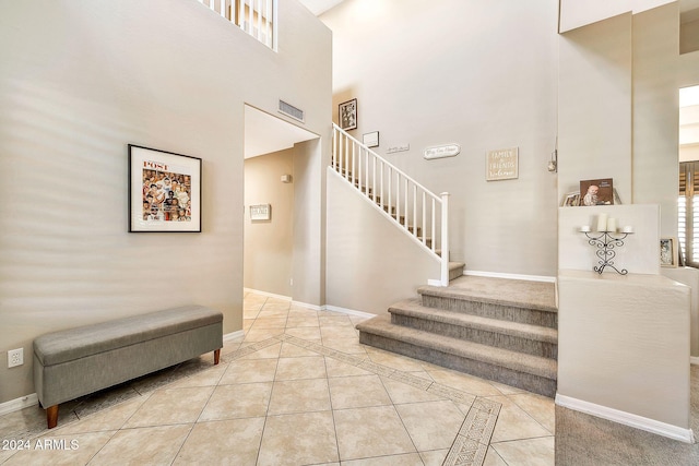 stairway with tile patterned flooring and a high ceiling