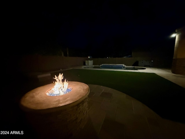 patio at night featuring a fenced in pool