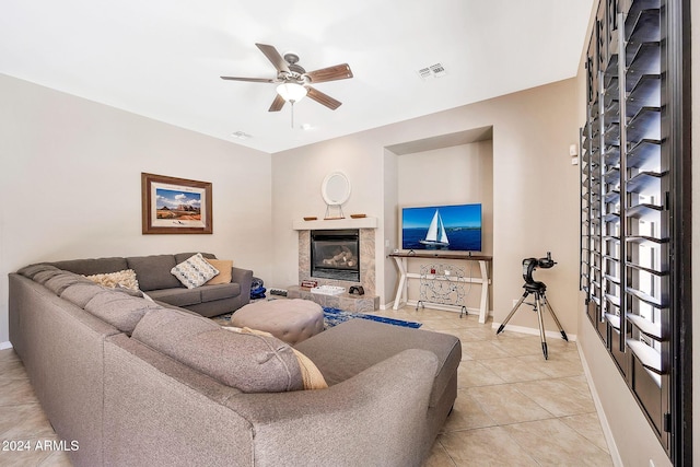 living room featuring a high end fireplace, ceiling fan, and light tile patterned flooring