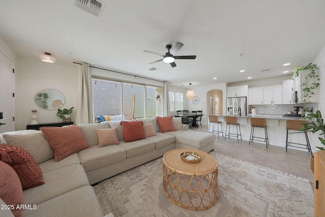 living area featuring arched walkways, recessed lighting, visible vents, light tile patterned flooring, and ceiling fan