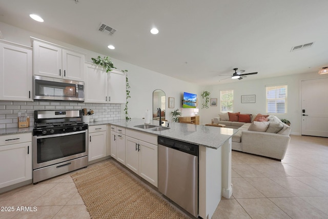 kitchen with light tile patterned floors, visible vents, a peninsula, stainless steel appliances, and backsplash