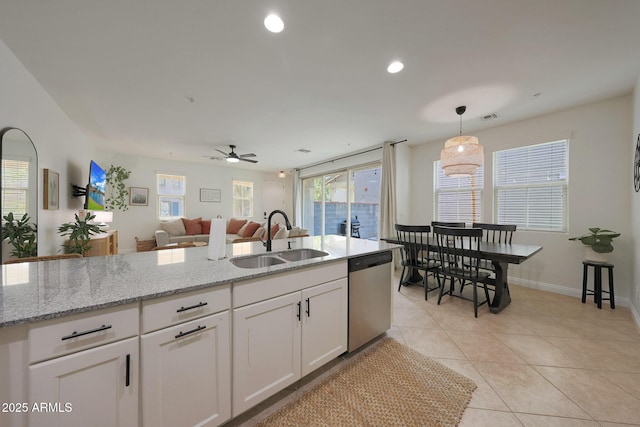 kitchen featuring white cabinets, dishwasher, light stone counters, a sink, and light tile patterned flooring