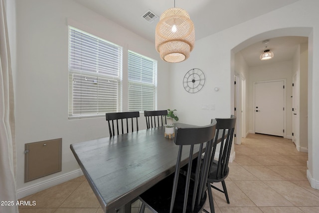 dining area featuring arched walkways, light tile patterned floors, visible vents, and baseboards