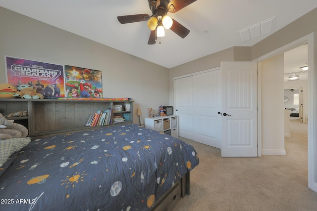 carpeted bedroom with vaulted ceiling, a closet, visible vents, and a ceiling fan