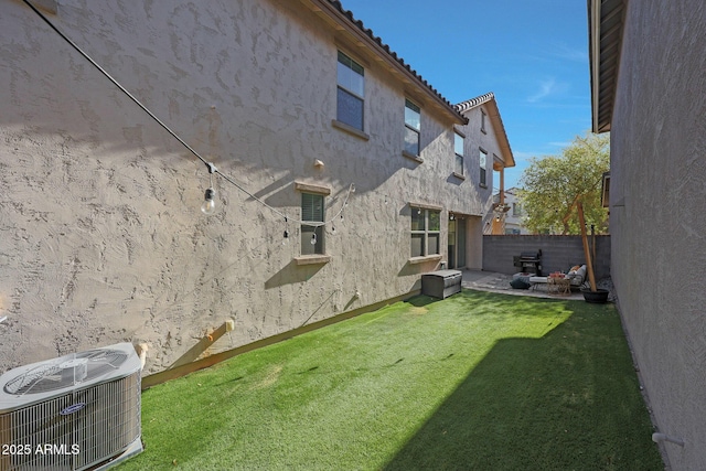 rear view of property featuring cooling unit, fence, a tile roof, a lawn, and stucco siding