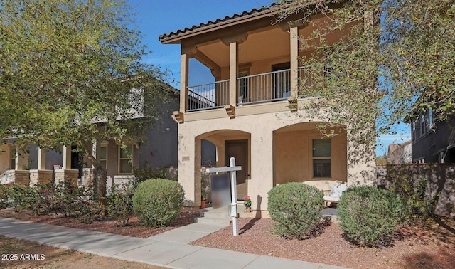 mediterranean / spanish-style home featuring a tile roof, a balcony, and stucco siding