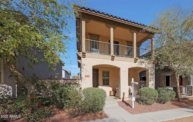 mediterranean / spanish home with a balcony, covered porch, and stucco siding