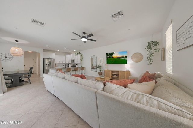 living area featuring light tile patterned floors, visible vents, and arched walkways