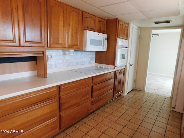 kitchen featuring decorative backsplash, light countertops, visible vents, white appliances, and brown cabinetry