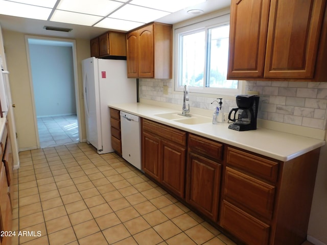 kitchen with light countertops, visible vents, white appliances, a sink, and backsplash