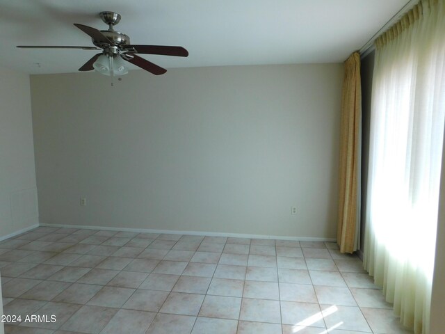 spare room featuring plenty of natural light, baseboards, light tile patterned flooring, and a ceiling fan