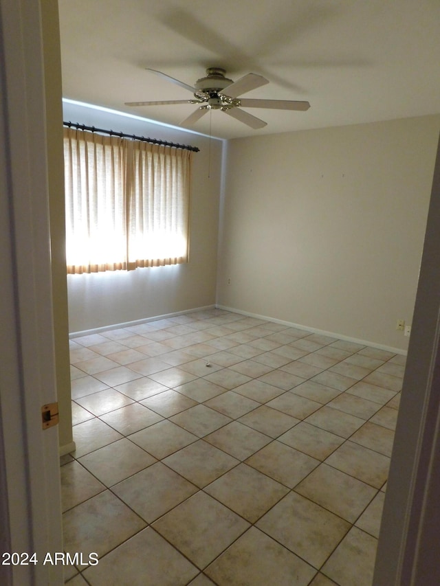 tiled spare room featuring ceiling fan