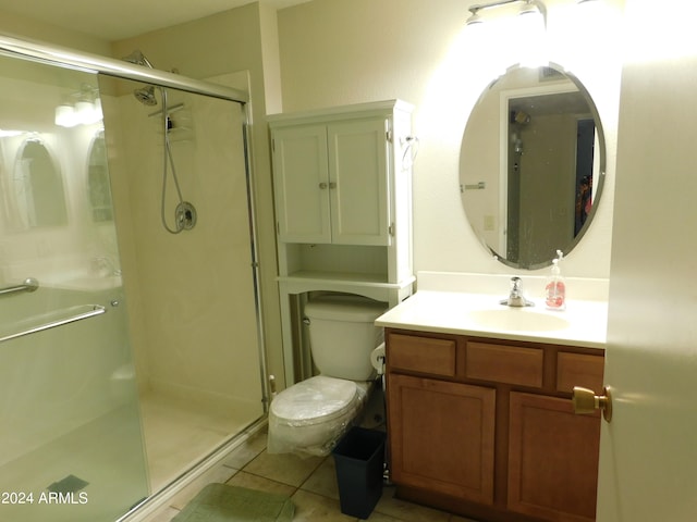 bathroom featuring tile patterned flooring, vanity, toilet, and a shower with shower door