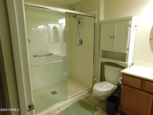 bathroom featuring toilet, walk in shower, vanity, and tile patterned floors