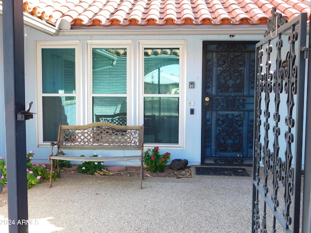 doorway to property featuring a tile roof and covered porch