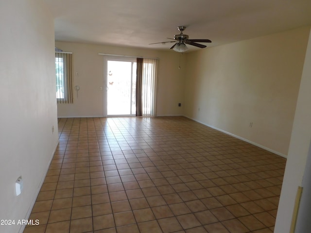 unfurnished room with baseboards, ceiling fan, and light tile patterned floors