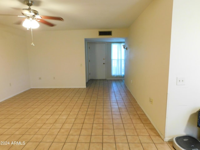 empty room featuring light tile patterned floors, visible vents, baseboards, and ceiling fan