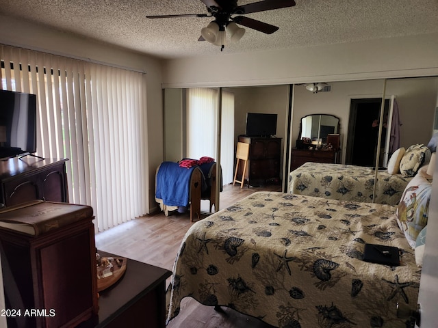 bedroom with ceiling fan, a closet, hardwood / wood-style flooring, and a textured ceiling