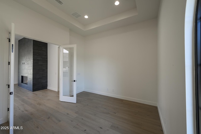 unfurnished room featuring visible vents, baseboards, recessed lighting, wood finished floors, and a raised ceiling