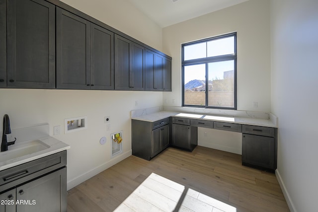 clothes washing area featuring hookup for a washing machine, light wood-style flooring, cabinet space, electric dryer hookup, and a sink