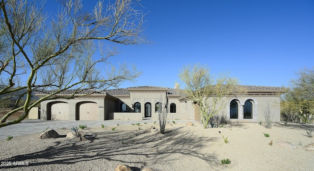 mediterranean / spanish house featuring stucco siding, decorative driveway, a garage, and a tile roof