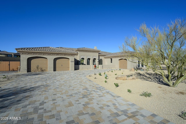 mediterranean / spanish-style home with a tile roof, decorative driveway, a garage, and stucco siding