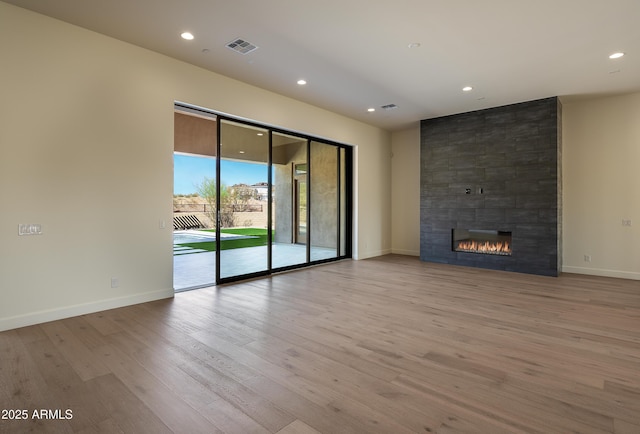 unfurnished living room featuring wood finished floors, visible vents, and baseboards