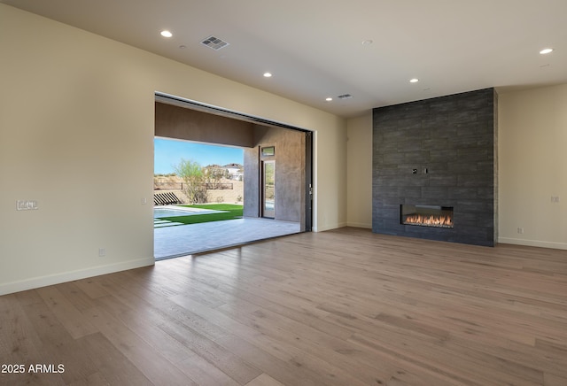 unfurnished living room featuring visible vents, wood finished floors, recessed lighting, a large fireplace, and baseboards