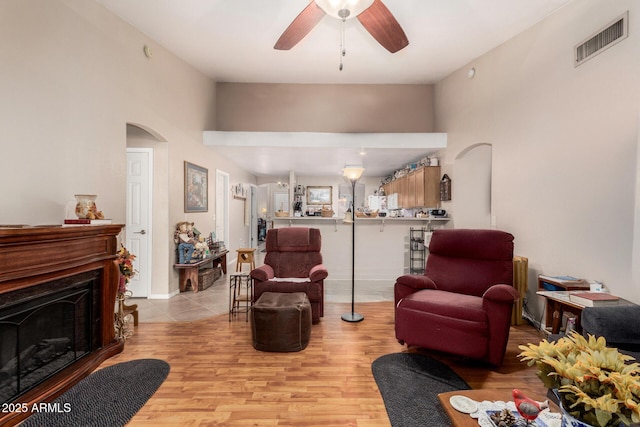 living area with arched walkways, visible vents, a fireplace, and a ceiling fan