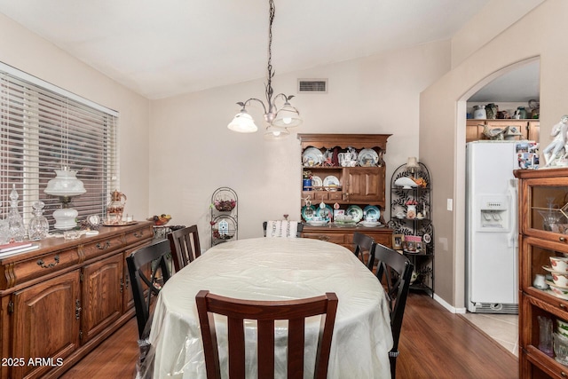 dining room featuring an inviting chandelier, arched walkways, visible vents, and dark wood-style flooring