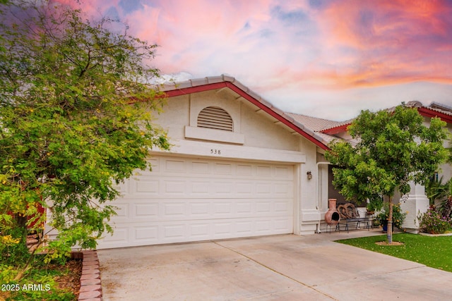 view of front of house featuring stucco siding, driveway, and a tile roof